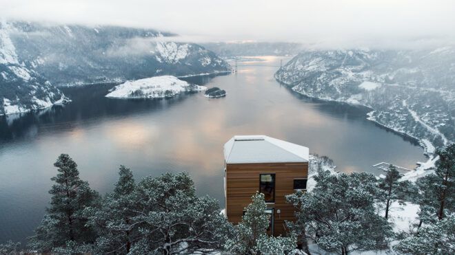 A cabin that overlooks an icy river and mountain range