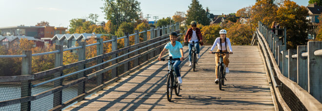 A group of three biking down a wooden bridge