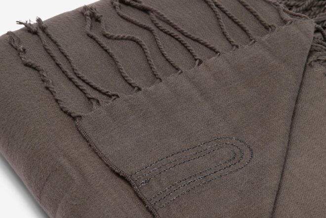 An up-close of a gray blanket with fringe ends
