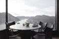 A round table with four seats facing a window of a mountain range scenery