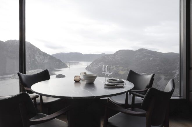 A round table with four seats facing a window of a mountain range scenery