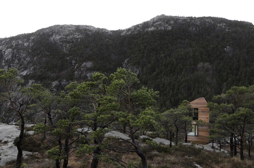 A cabin hidden in a forest and mountain range