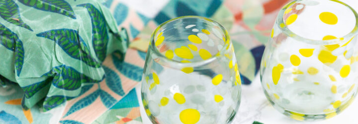 Two glasses decorated in yellow with silk sheets next to it