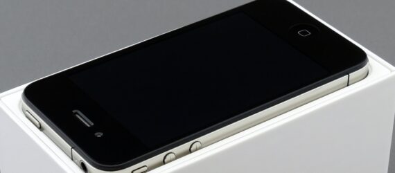 An iPhone turned off and laying on a white pedestal box