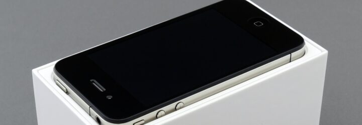 An iPhone turned off and laying on a white pedestal box