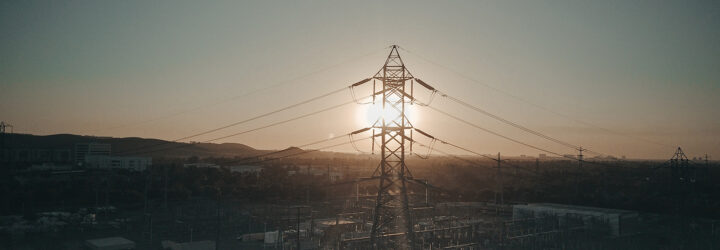 An electrical pole with wires coming out of it overlooking a sunset scenery