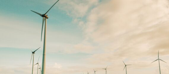 Two rows of wind turbines against a blue and cloud sky