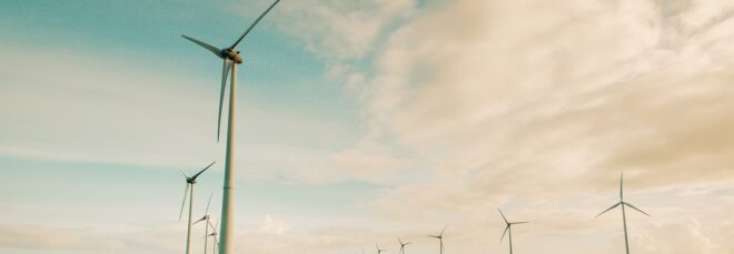 Two rows of wind turbines against a blue and cloud sky