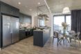Kitchen with dark green cabinetry and dining space with rattan furniture in modern apartment