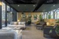 Lounge space with multiple seating configurations, dotted with planters. Glass door on the left leads to a terrace