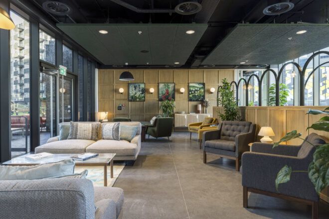 Lounge space with multiple seating configurations, dotted with planters. Glass door on the left leads to a terrace