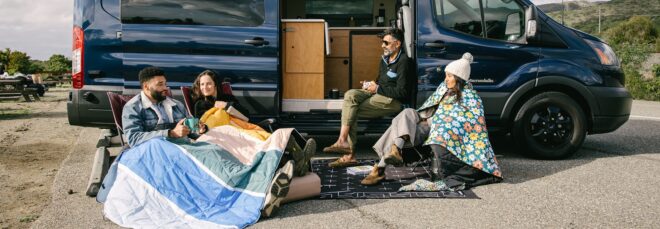 A group of people sitting beside a van