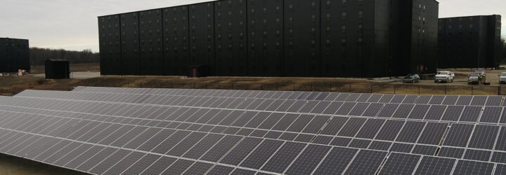 Rows of solar panels in front of a black distillery building