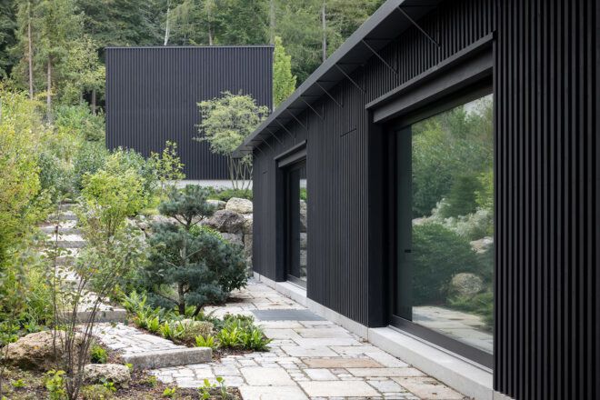 The side of a black home overlooking a garden