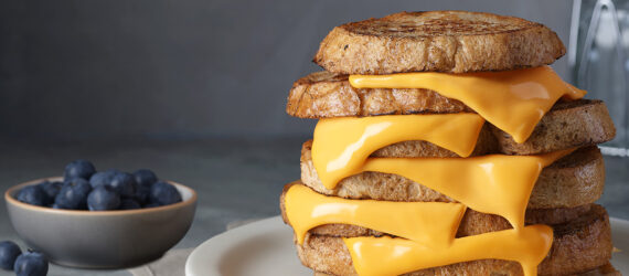 A six layer grilled cheese sandwich with a bowl of blueberries next to it