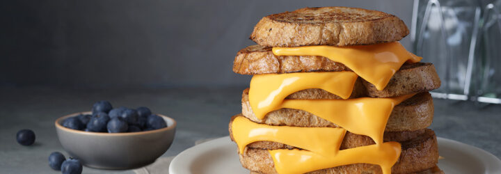 A six layer grilled cheese sandwich with a bowl of blueberries next to it