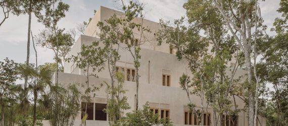A cream colored home and resort hidden behind trees
