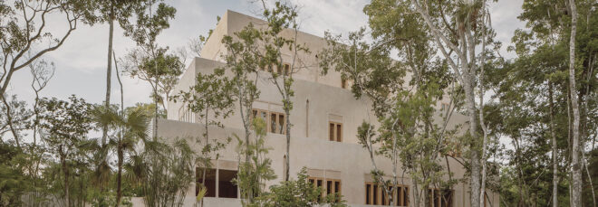 A cream colored home and resort hidden behind trees