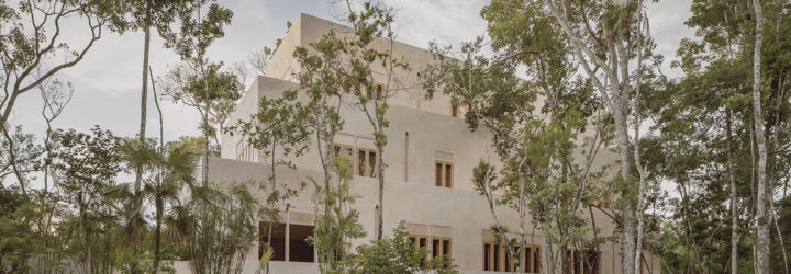 A cream colored home and resort hidden behind trees