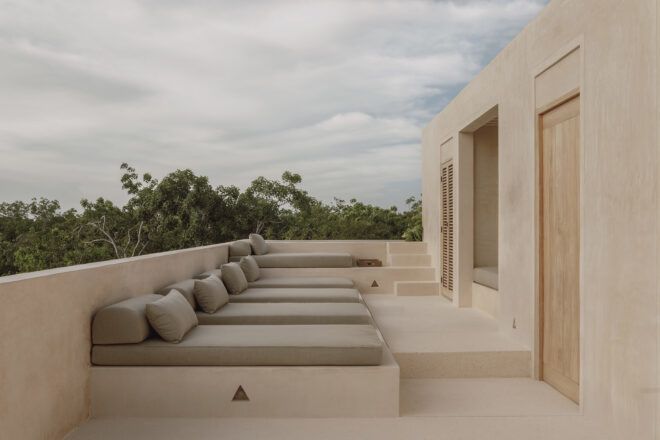 Lounging chairs set against a wall facing a cream-colored building