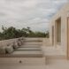 Lounging chairs set against a wall facing a cream-colored building