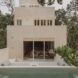 A cream colored home with a backyard pool and lounging area