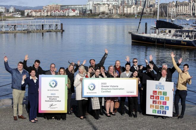 A group of people standing beside a body of water holding three different signages
