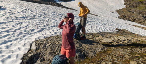 Two backpackers with their backpacks on the ground looking into the distance on a mountain range