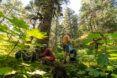 Two people standing and squatting within a forest