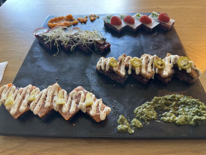 An assortment of vegan sushi on a black platter