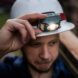 A person wearing a white safety helmet with a headlamp attached to it