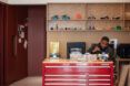 Boy painting at a tall, red desk in front of shelving with 3D printers and 3D printed designs