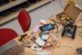 Cluttered workspace with a laptop, wires, robots, tablet, and keyboard for STEM activities