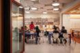 Open plan classroom where students are seated and collaborating at three tables