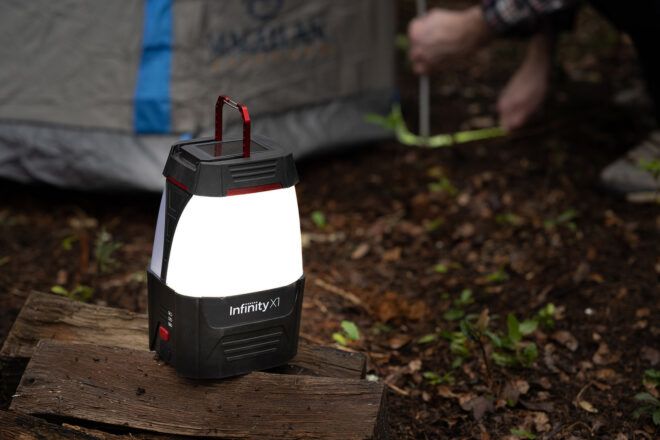 A lamp set on a log beside a tent