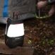 A lamp set on a log beside a tent