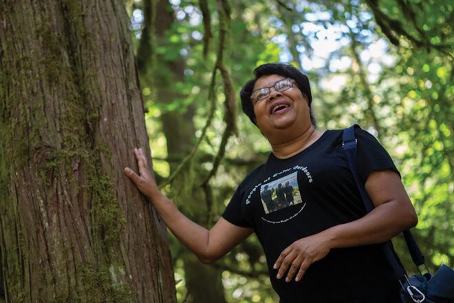 A woman leaning against a tree in a forest