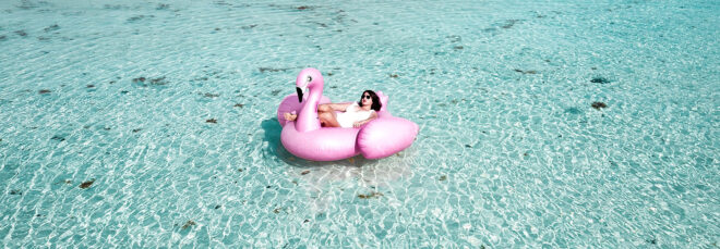 A person floating in a pink flamingo floaty in a pool