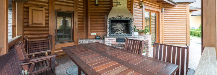 A wooden cabin with wood furniture and a brick fireplace