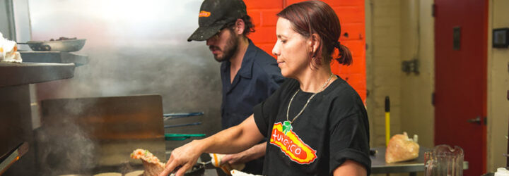 A man and a woman cooking in a crowded kitchen