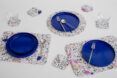 A variety of placemats and coasters with plates and utensils and cups on top of them