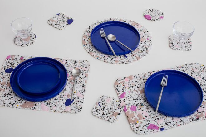 A variety of placemats and coasters with plates and utensils and cups on top of them