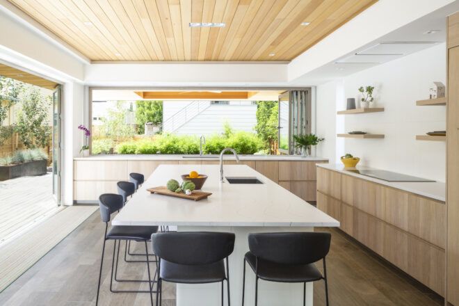 Kitchen island with tall black seats with views out from the folding doors and windows