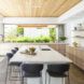 Kitchen island with tall black seats with views out from the folding doors and windows