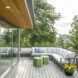Terrace on the upper level that wraps around a corner. Features a corner couch and green hexagonal coffee tables