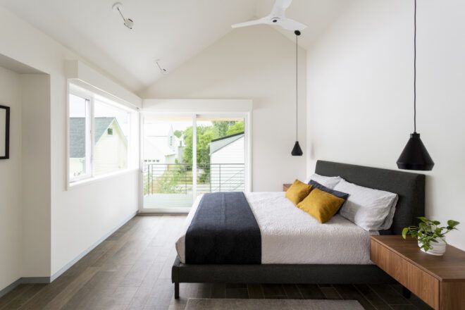 Bedroom interior with a slanted ceiling that has windows and a door leading out to a terrace