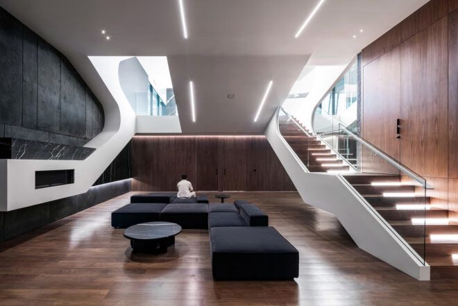 A living room area with black sofas and a staircase