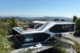 A two story home with an outdoor deck overlooks a valley range