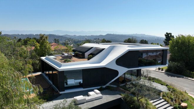 A two story home with an outdoor deck overlooks a valley range