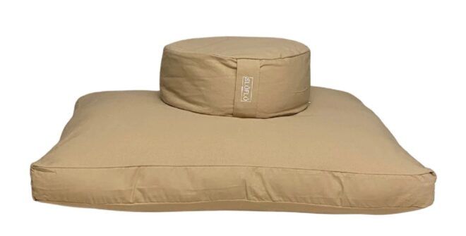 A tan circular cushion on top of a square cushion